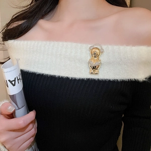 Close-up of a sparkling gold bear brooch with crystals pinned on a knitted sweater