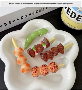 Detailed view of creative food-shaped hair clips including edamame and meat skewers