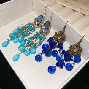 Detail view of bohemian fringe earrings with blue beads and shell charms in a jewelry box