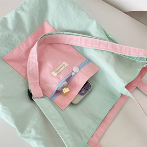 Internal detail of a pastel tote bag showing storage for phone and cosmetics