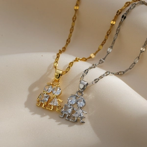 Close-up of gold and silver twin girl pendants with sparkling zircons on silk fabric