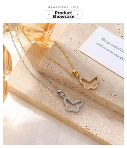 Detail of gold and silver butterfly necklaces with white zircons on a textured stone