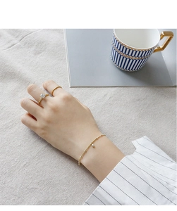 Elegant gold jewelry set with pearl bracelet and four-claw square stone ring on gray linen