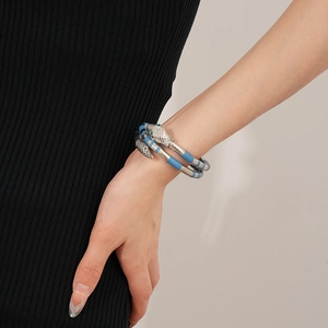 Detail of silver snake ring with blue stripes and green crystal eyes on a model hand