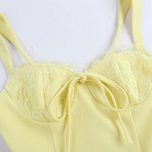 Détail de la robe jaune avec dentelle raffinée au décolleté et bretelles à nœuds