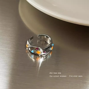Macro shot of silver adjustable star ring with colorful enamel and hammered texture metal