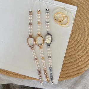Detailansicht von drei eleganten Ovaluhren mit doppelreihigen Perlenarmbändern in versch. Farben