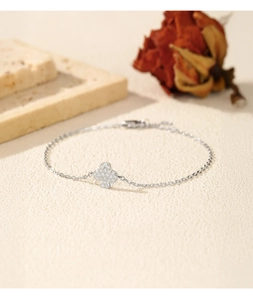 Detail of silver clover bracelet with sparkling clear stones on a textured background