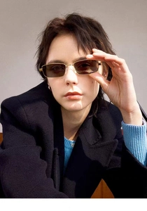 Detalle de gafas de sol rectangulares doradas con lentes teñidas en una modelo de moda