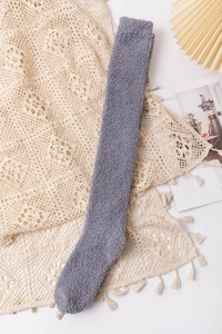 Detail of grey coral fleece over-knee socks with soft plush texture on lace background