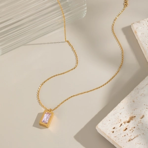 Detail of gold necklace with a rectangular pendant and sparkling pink zircon stone