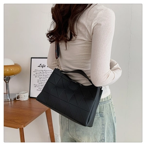 Detail of black geometric PU leather bag with colorful woven wide shoulder strap