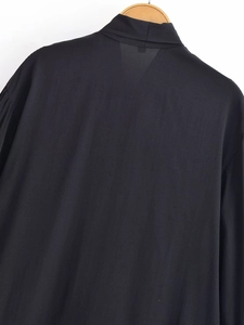 Detailed view of the black bow-tie blouse collar and back texture on a wooden hanger