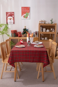 Close-up of red and green plaid Christmas tablecloth with tassels on a decorated table