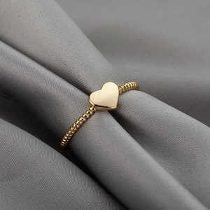 Macro shot of 18k gold plated heart ring with elegant beaded spiral texture on satin
