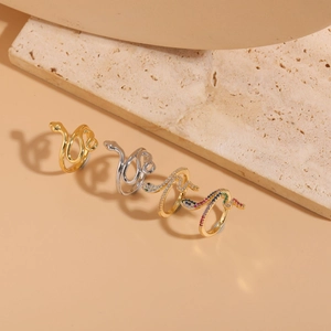 Detailed view of four serpent rings with zircon settings in gold and silver finishes