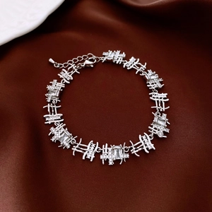 Detail of silver rectangle link bracelet with zircon inlay on brown silk fabric