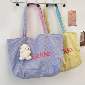 Detail of color-block canvas tote bag with zakka embroidery and cute plush sheep pendant