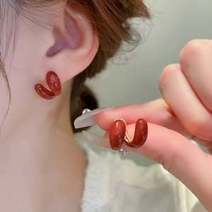 Gros plan de boucles d'oreilles torsadées en C rouge vin avec glaçure brillante