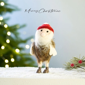 Christmas gnome doll figurine with red hat on snow background, festive tabletop decor