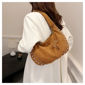 Gros plan d'un sac hobo en daim marron avec rivets argentés et patch en forme de cœur