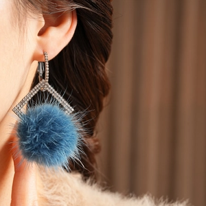 Detail of silver needle earring with navy blue pompom and sparkling diamond accents