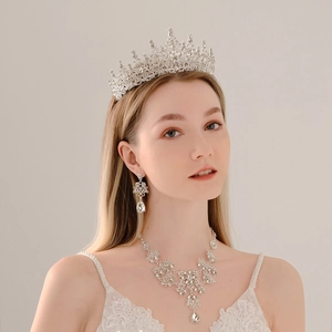Elegant bridal jewelry set featuring a silver rhinestone crown necklace and earrings on model