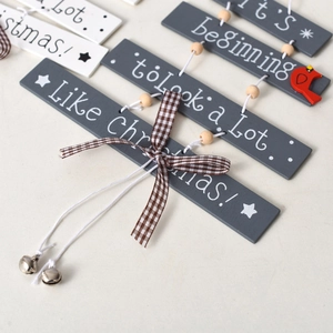 Close-up of grey and white wooden Christmas signs with plaid bows and bells