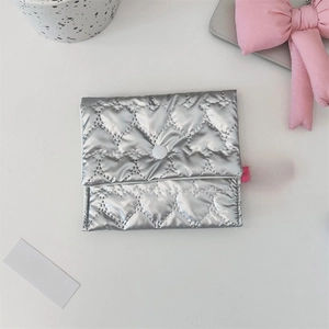 Detail of silver heart-quilted pouch with pink lanyard handle and button closure