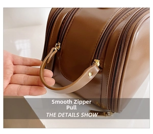 Detail of smooth gold metal zippers and sturdy handle on dark brown leather makeup bag