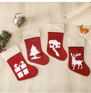 Detailed view of four red burlap Christmas stockings with white applique on wood floor