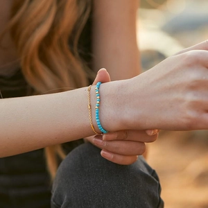 Adjustable turquoise beaded bracelet set with gold metal accents on female wrist