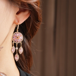 Close-up of vintage gold tassel earrings with pink zircons worn by a model