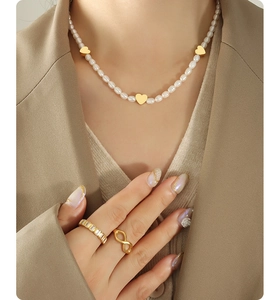 Close-up of elegant freshwater pearl necklace with heart pendants and gold rings