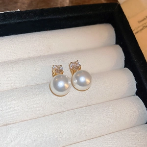 Close-up of pearl and zircon stud earrings on beige velvet display for luxury presentation