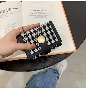 Close-up of houndstooth foldover wallet with premium gold buckle and leather trim