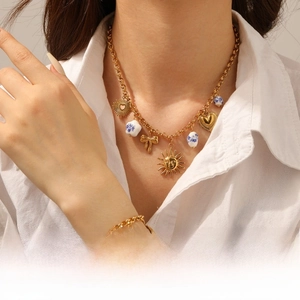 Detail of a gold sun, heart, and ceramic bead necklace and bracelet set on a model
