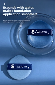 Detail of two sea blue teardrop makeup sponges with logo ribbons in a glass bowl