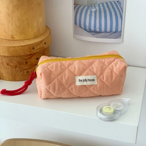 Detail of pink checkered quilted makeup bag with yellow zipper and red knot puller