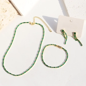 Gold plated emerald zircon jewelry set with necklace earrings and bracelet on stone props