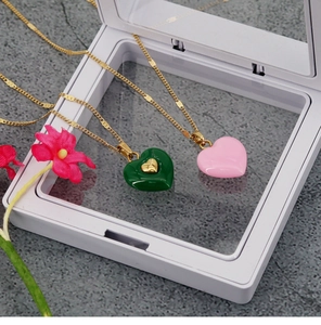 Close-up of pink and green heart pendant necklaces with elegant gold chains on a display