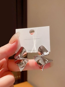 Détail des boucles d'oreilles géométriques en argent S925 sur une carte de présentation