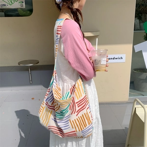 Outdoor street view of a large canvas tote bag with colorful artistic stripes and straps