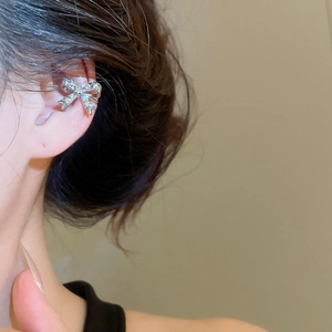 Dettaglio di un ear cuff a fiocco argento con zirconi scintillanti sull'orecchio