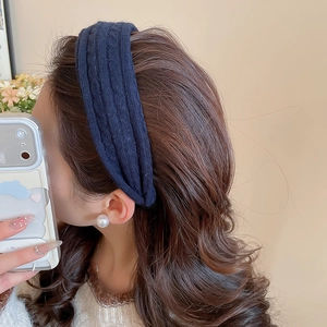 Détail d'un bandeau en maille côtelée bleu marine et d'une boucle d'oreille perle