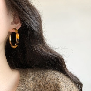 Macro view of tortoiseshell resin C-shaped hoop earring with gold metallic accents