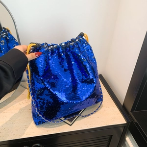 Detail of blue sequin drawstring bucket bag with gold chain strap and yellow cord handle