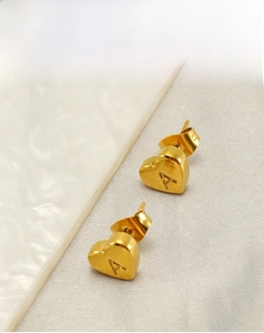 Detail of 18K gold-plated heart earring featuring a raised letter A on fabric background