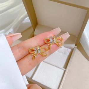 Detail of gold bow earrings featuring a rectangular zircon and micro-pave crystals