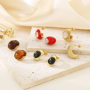 Set of elegant amber, cat eye, and textured gold earrings on a decorative stone stand
